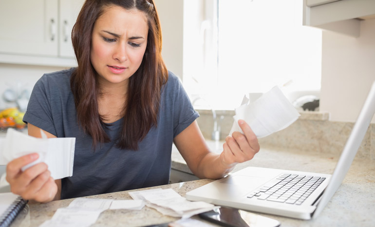 young woman getting stressed over finances in kitchen