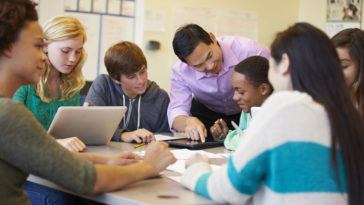 High School Students With Teacher In Class Using Laptops