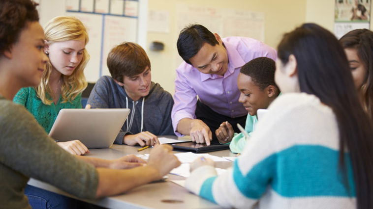 High School Students With Teacher In Class Using Laptops